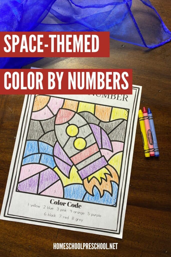 sample page colored in of space themed color-by-number sitting on a table with 3 primary crayons