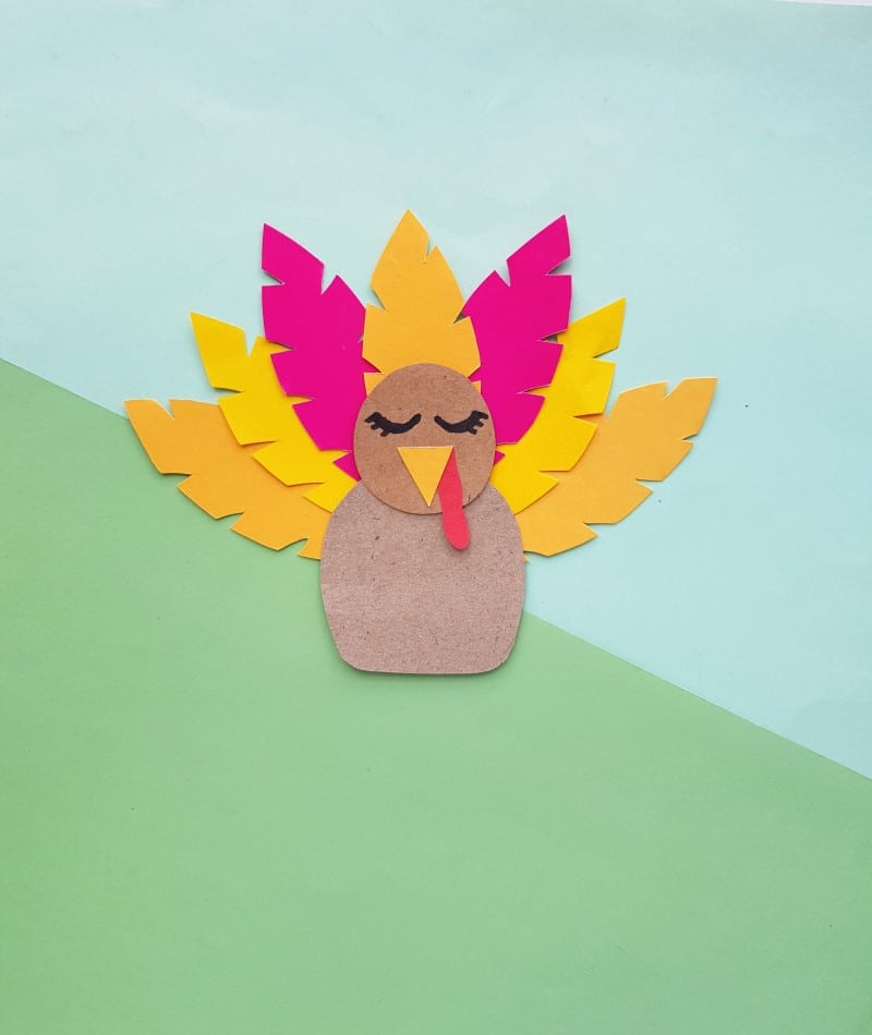 image of completed turkey craft with yellow and red feathers on blue and green background