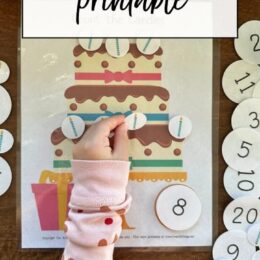 a young girls hand putting numbers on a printed birthday cake to practice counting